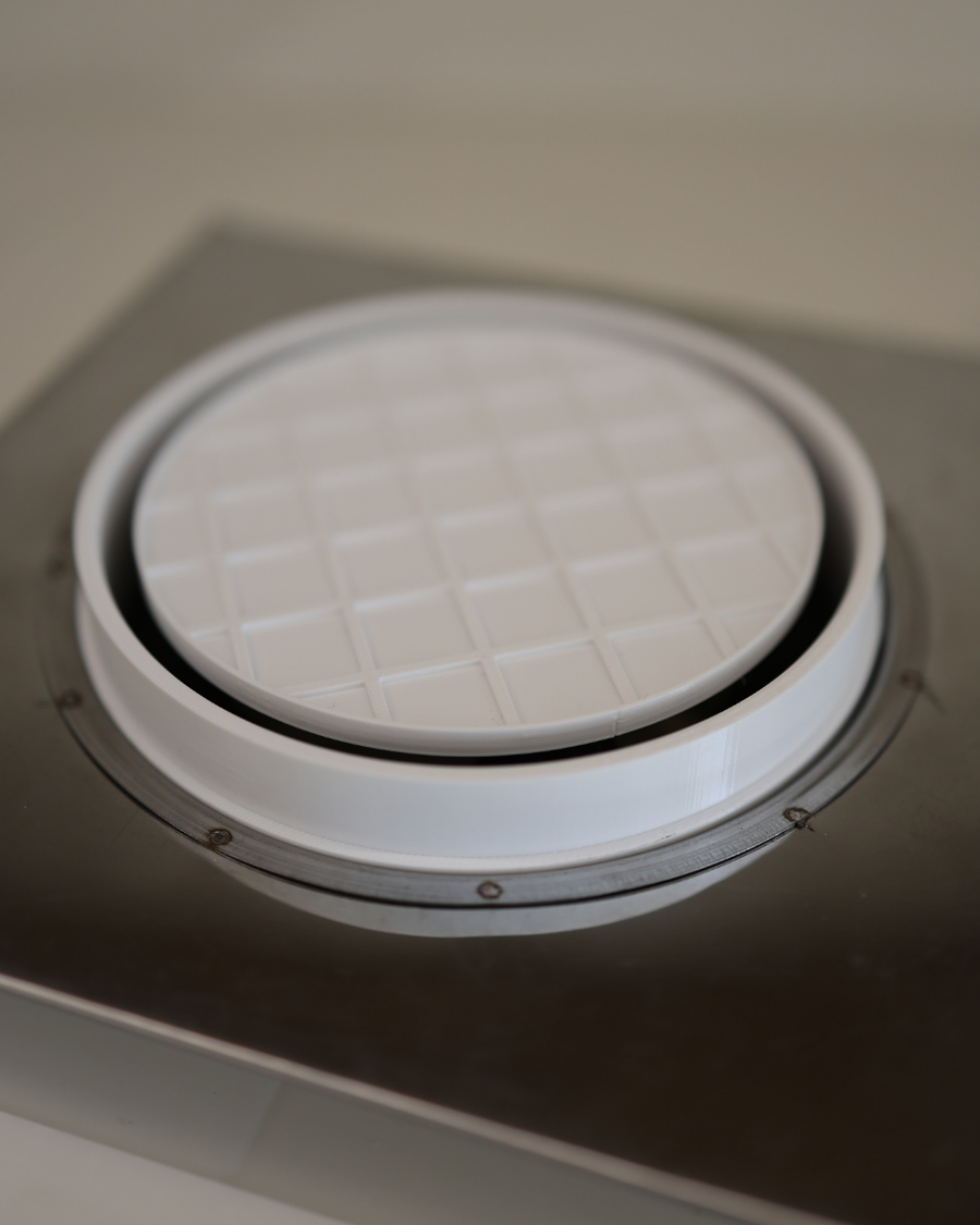 Close-up of GRATKA SLIM 125 textured grille panel installed flush in drywall ceiling, designer ventilation cover